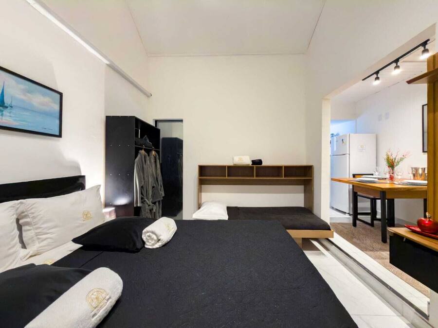 Una habitación de hotel moderna con dos camas, un armario, una kitchenette pequeña y una zona de comedor.