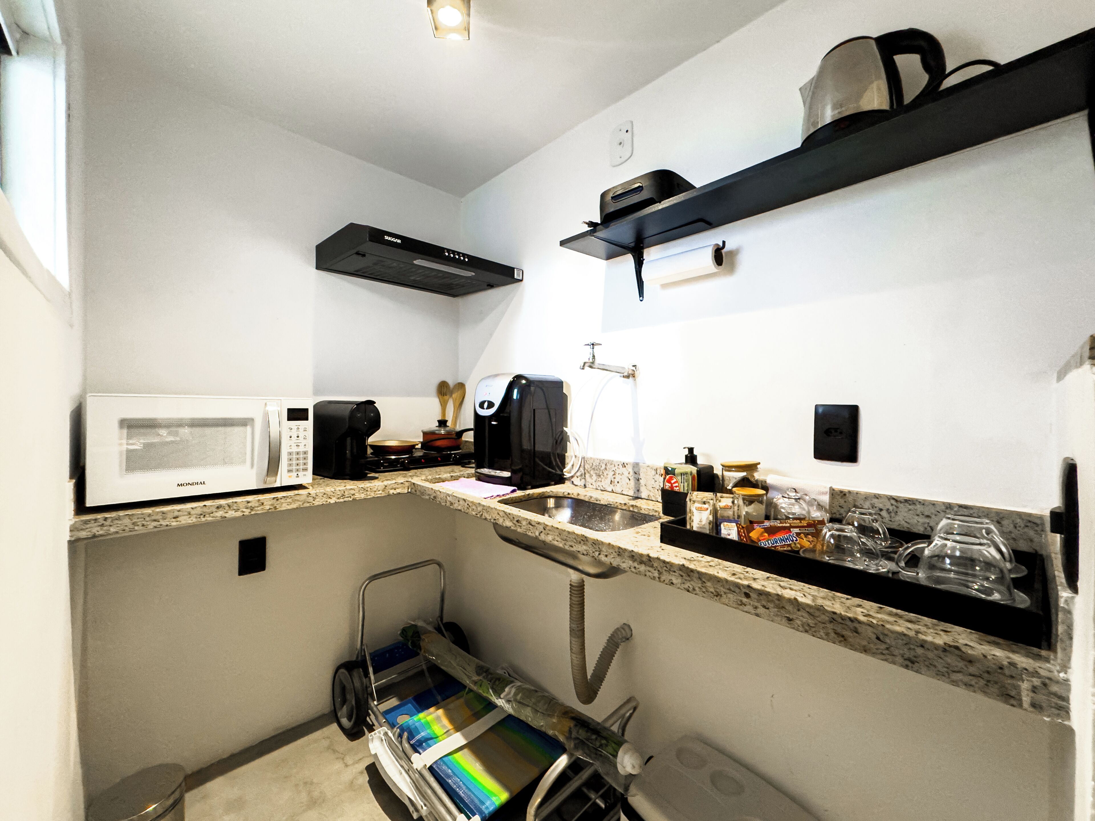A compact kitchen with a microwave, coffee maker, and a small sink.