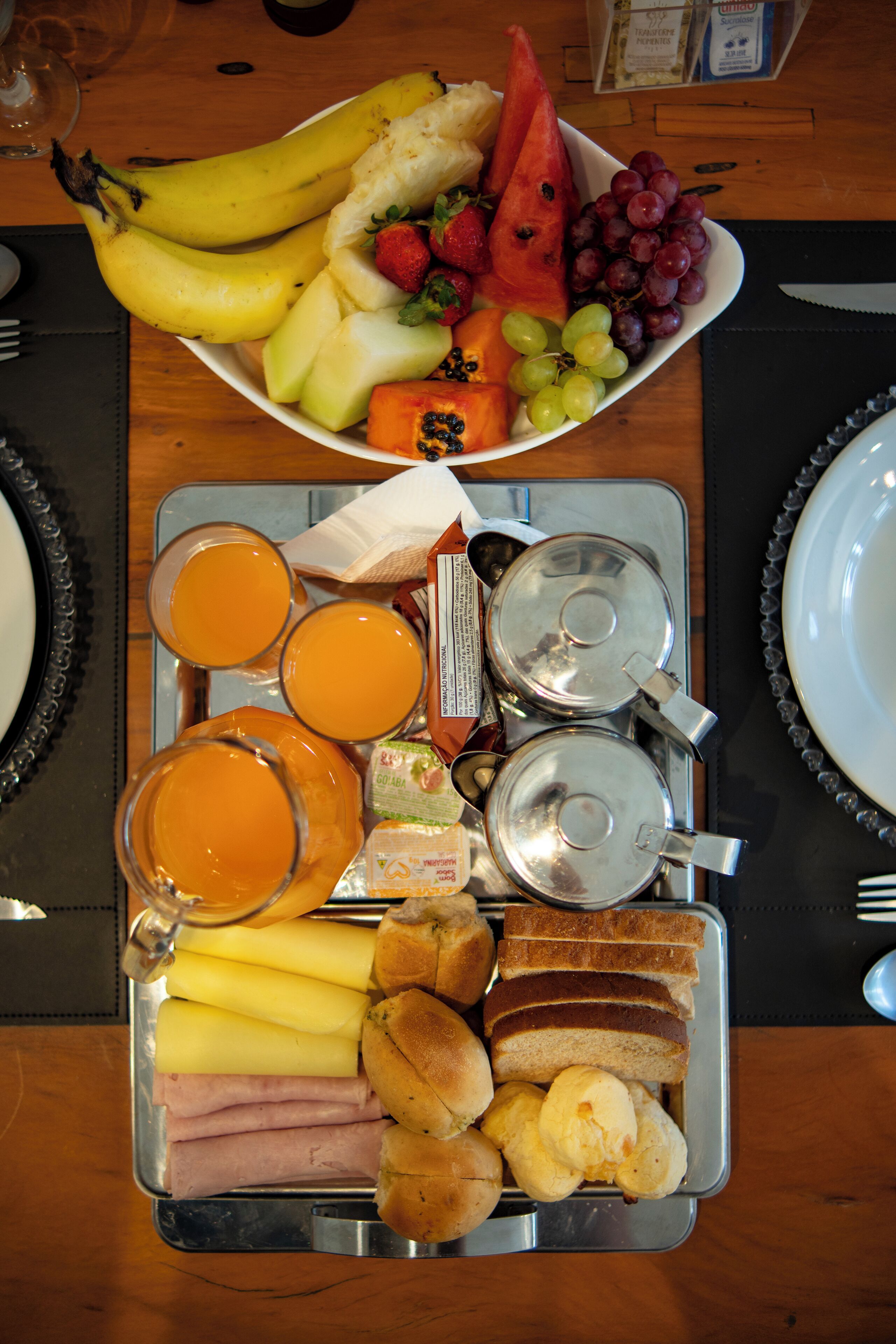 Un plateau de petit-déjeuner avec des fruits, du pain et des boissons.