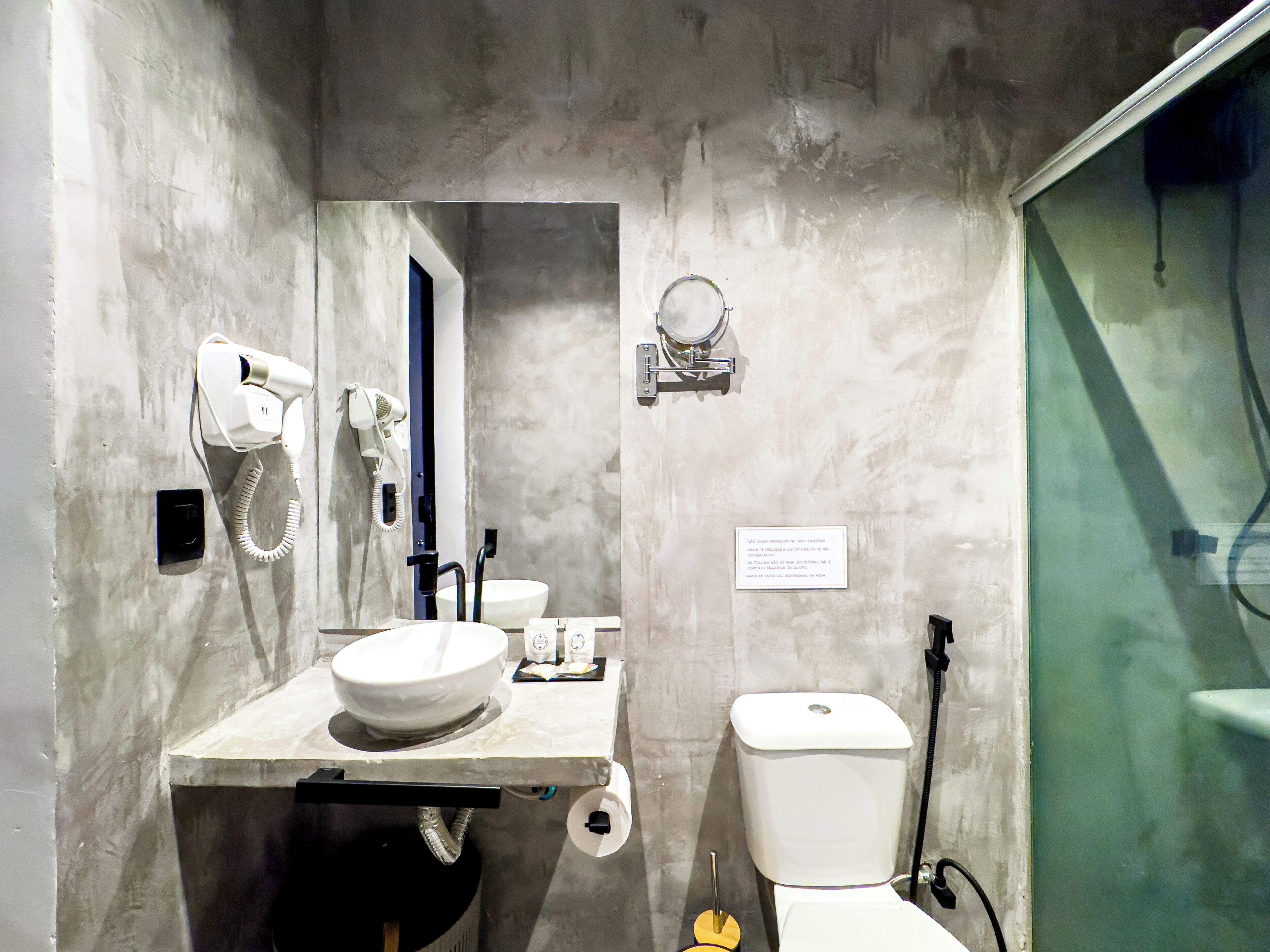Une salle de bain avec un lavabo blanc, des toilettes et un sèche-cheveux fixé au mur.