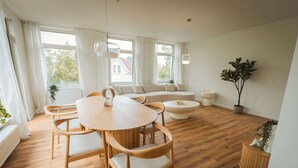 A modern living room with a round wooden table, two sofas, and a coffee table.