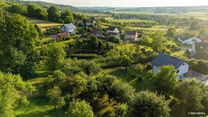 An aerial view of a rural village with houses surrounded by lush greenery and fields.