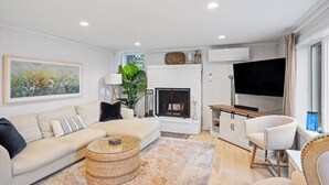 A modern living room with a sofa, a coffee table, a fireplace, a television, and a large window.