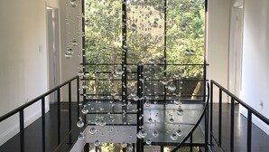 A modern staircase with a glass railing and hanging glass spheres.