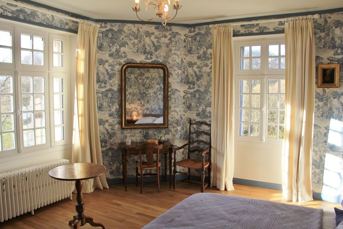 Ein Zimmer mit einem Bett, einem Tisch, zwei Stühlen, einer Heizung und einem großen Spiegel.