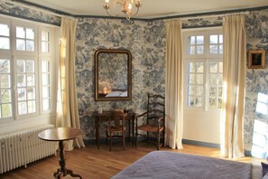 Ein Zimmer mit einem Bett, einem Tisch, zwei Stühlen, einer Heizung und einem großen Spiegel.