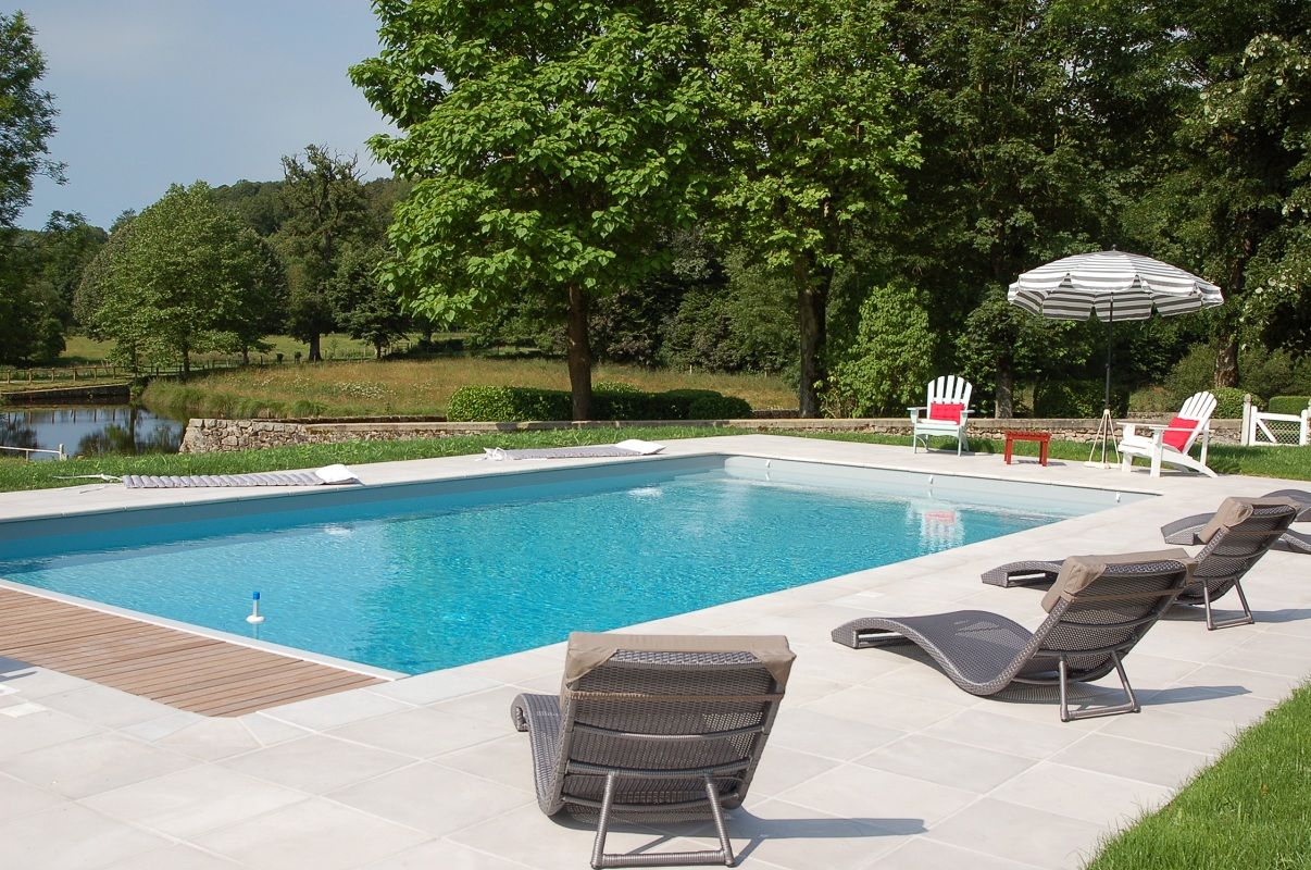 Ein rechteckiger Swimmingpool mit Liegestühlen und einem Sonnenschirm.