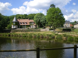 A riverside property with a stone house, a wooden fence, and a pond. - Exceptional family home in the Creuse department (Saint-Vaury)