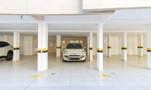 A parking garage with white pillars and yellow directional arrows on the floor. - Apart w/ Barbecue in Condominium With Pool Bri0102 (Florianópolis)