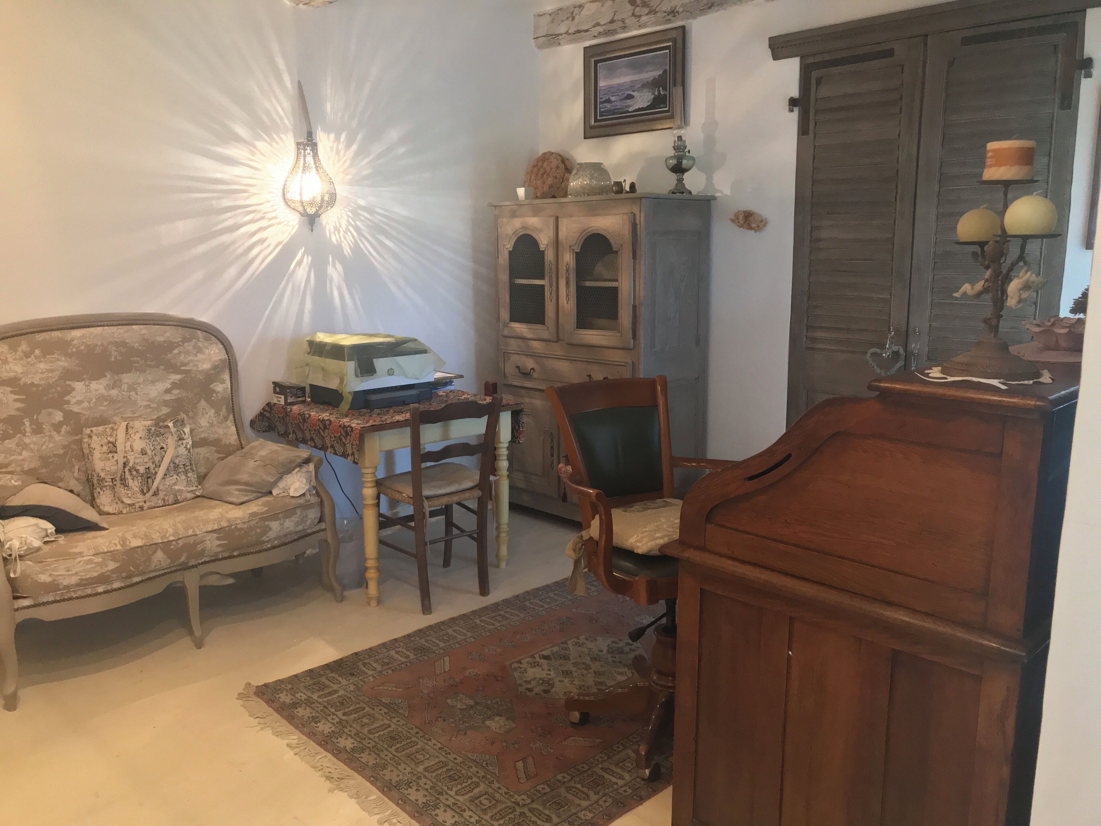 Ein gemütliches Wohnzimmer mit einem Vintage-Sofa, einer Holzkommode und einem kleinen Tisch mit einer Lampe.