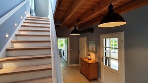 A staircase with wooden steps and white walls, a wooden dresser, and pendant lights.