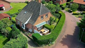 Une maison à deux étages, dotée d’un toit en pente, d’un porche à l’avant et d’un jardin bien entretenu.