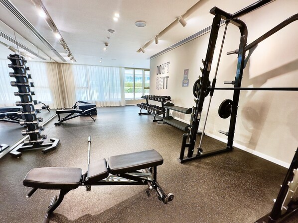 A gym with various exercise equipment, including dumbbells, benches, and a squat rack.