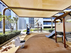 A children's playground with a slide, climbing structures, and a stroller.