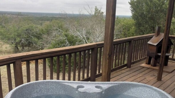 A hot tub on a wooden deck with a view of a natural landscape.