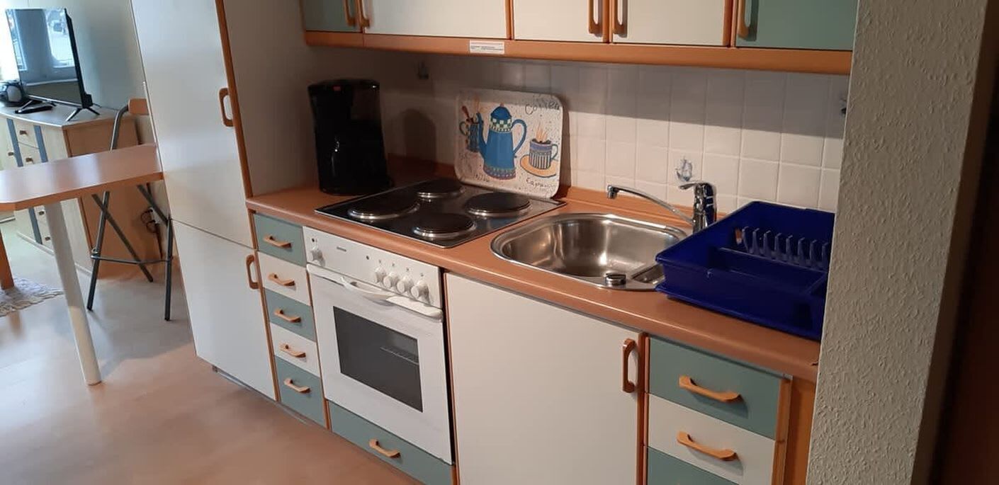 Pieni, käytännöllinen keittiö, jossa on liesi, uuni ja pesuallas.