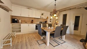 A modern kitchen with white cabinets, a wooden countertop, and a dining table with four chairs.