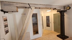 A hallway with a wooden ceiling beam, a frosted glass door, and a black column.