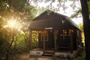 A rustic log cabin with a porch, labeled "Yellestone," surrounded by dense forest.