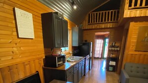 L’intérieur d’une cabine comprend une table à manger en bois, un coin cuisine équipé d’appareils électroménagers et un canapé.