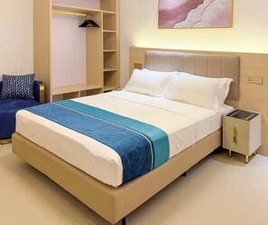 Hotellihuone, jossa on sänky, yöpöytä ja vaatekaappi.