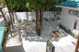 Un patio con un muro blanco, un árbol y una pequeña mesa con sillas.