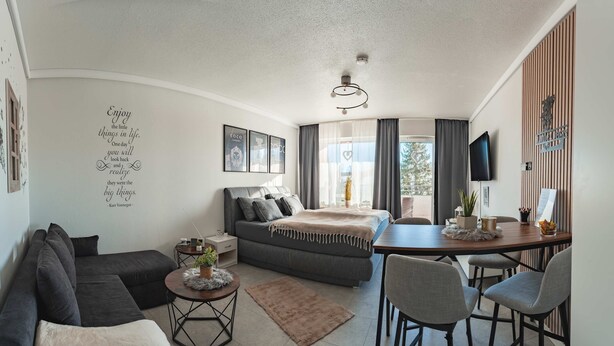 A modern, compact living space with a sofa, a small round table, a bed, and a dining area. - Little Oasis Brilon-Willingen (Brilon)