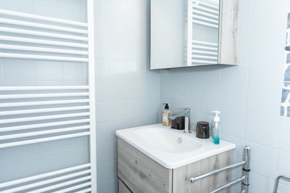 A bathroom with a white sink, a mirror, and a towel rack.