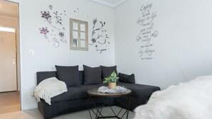 A modern living room with a dark grey sofa, a round coffee table, and decorative wall art. - Little Oasis Brilon-Willingen (Brilon)
