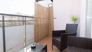 A balcony with wicker furniture, a glass table, and a bamboo fence. - Little Oasis Brilon-Willingen (Brilon)