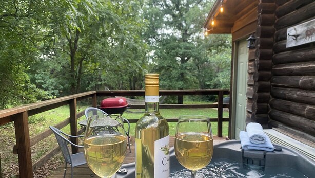 A wooden deck with a table, two wine glasses, and a bottle of wine. - Secluded Escape with a hot tub, surrounded in nature (BLUFFDALE)