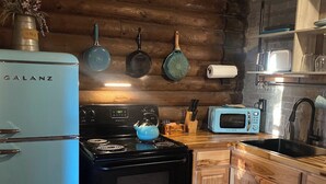 A kitchen with a Galanz refrigerator, a black stove, a blue kettle, a microwave, and wooden cabinets. - Secluded Escape with a hot tub, surrounded in nature (BLUFFDALE)