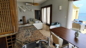 A modern kitchen with a granite countertop, stainless steel sink, and a dining area with a wooden table and chairs. - Charming 2bdrm/2bath beachfront PH Condo WiFi, AC, TV, beach lounges included (Philipsburg)