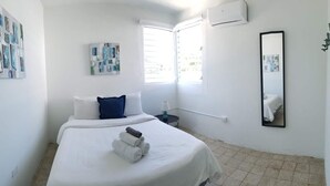 A hotel room with a bed, a nightstand, a mirror, and artwork on the walls. - Private Pool Piscina Privada by CasaSaffra (San Juan)