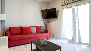 A living room with a red sofa, a black coffee table, a flat-screen TV mounted on the wall, and a sign reading "BEACHHOUSE". - 5 Bedroom with Private Pool NEXT TO BEACH (San Juan)
