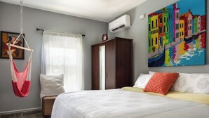 A bedroom with a bed, a hanging chair, a wardrobe, and a colorful painting on the wall. - 5 Bedroom with Private Pool NEXT TO BEACH (San Juan)