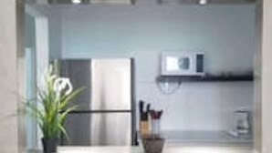 Een moderne keuken met een inbouwkoelkast, magnetron en een klein aanrecht.