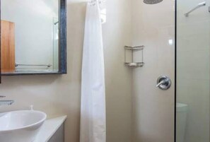 A bathroom with a white sink, a mirror, a shower enclosure, and a glass door. - This listing is for two (2) spacious  homes, next to each other (San Juan)