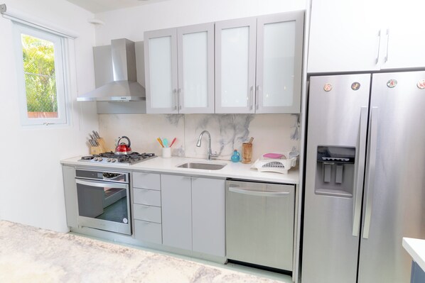 A modern kitchen with stainless steel appliances, a built-in oven, a dishwasher, and a water dispenser.