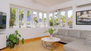 A modern living room with a sofa, a round coffee table, and potted plants. - Extra Large Spacious Beach House with Solar Panels and 800 gallon cistern (San Juan)