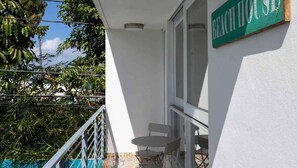 A balcony with a tiled floor, a small table, and a chair. A sign on the wall reads "BEACH HOUSE." - Extra Large Spacious Beach House with Solar Panels and 800 gallon cistern (San Juan)