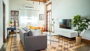 Een woonkamer met een bank, televisie en decoratieve planten.