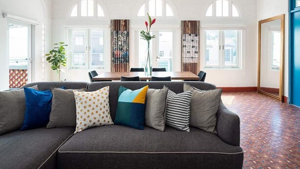 Una sala moderna con un sofá gris, una mesa de comedor y ventanas de arco.