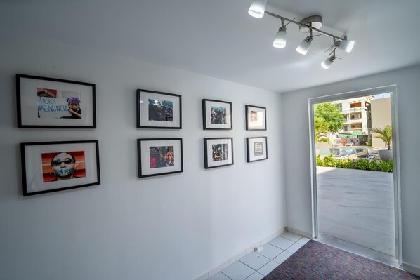 A hallway with framed pictures on the wall and a door leading outside.