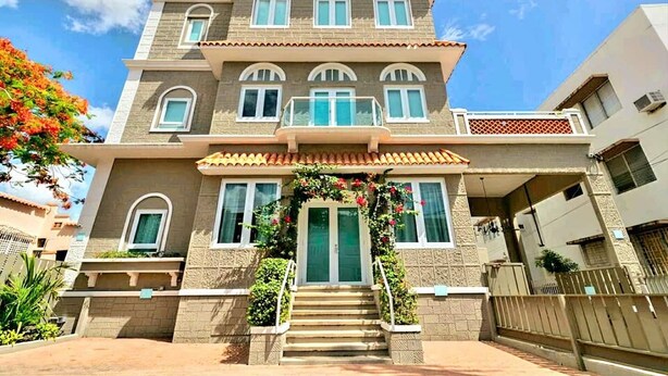A two-story building with a balcony, a front entrance with steps, and a tiled roof.