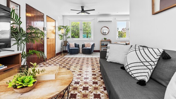 A modern living room with a grey sofa, a patterned rug, and a ceiling fan. - Location is Everything  3and a Half  Bedroom (San Juan)