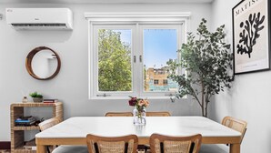 A dining area with a white table, four wicker chairs, a small plant, and a framed artwork on the wall. - Location is Everything  3and a Half  Bedroom (San Juan)