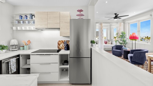 A modern kitchen with white cabinetry, a stainless steel refrigerator, and a dining area with a table and chairs. - Tropical San Juan Life with Pool (San Juan)