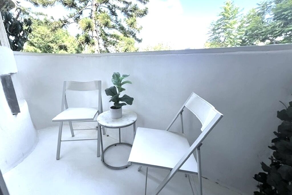 Ein kleiner Balkon mit zwei weißen Stühlen und einem Blumentopf.