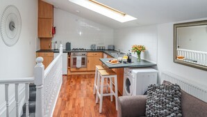Eine moderne Küche mit Holzausstattung, einem Einbauofen und einem Essbereich mit Tisch und Stühlen.